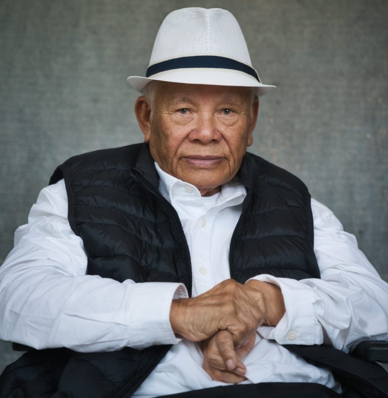 Motorradfahrer in buntem Outfit fährt über einen unbefestigten Boden.